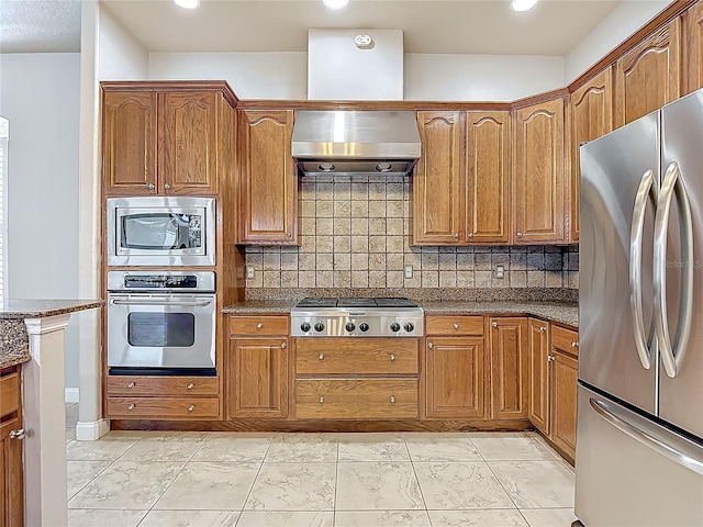 13110 Manistee Rd, Weeki Wachee, FL 34614 - kitchen with appliances with stainless steel finishes, wall chimney range hood, brown cabinets, and recessed lighting