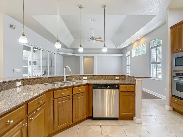13110 Manistee Rd, Weeki Wachee, FL 34614 - kitchen featuring stainless steel appliances, a sink, a tray ceiling, a ceiling fan, and brown cabinets
