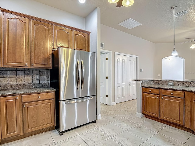 13110 Manistee Rd, Weeki Wachee, FL 34614 - kitchen featuring freestanding refrigerator, brown cabinetry, backsplash, and a textured ceiling