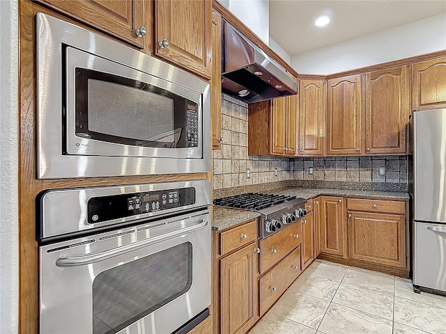 13110 Manistee Rd, Weeki Wachee, FL 34614 - kitchen with appliances with stainless steel finishes, exhaust hood, decorative backsplash, and dark stone countertops
