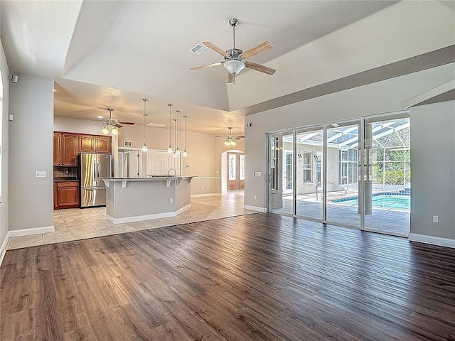 13110 Manistee Rd, Weeki Wachee, FL 34614 - unfurnished living room featuring ceiling fan, light wood-style flooring, baseboards, a sink, and high vaulted ceiling