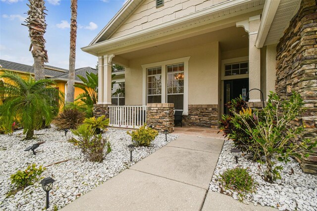 7410 Ambleside Dr, Land O Lakes, FL 34637 - view of exterior entry featuring a porch, stone siding, and stucco siding