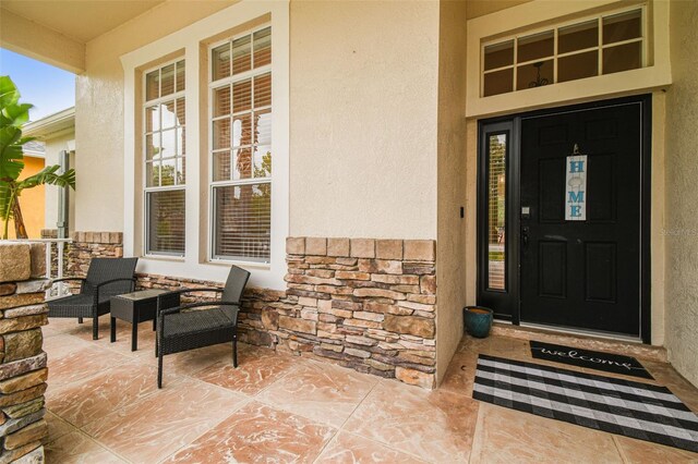 7410 Ambleside Dr, Land O Lakes, FL 34637 - property entrance featuring stucco siding, a porch, and stone siding