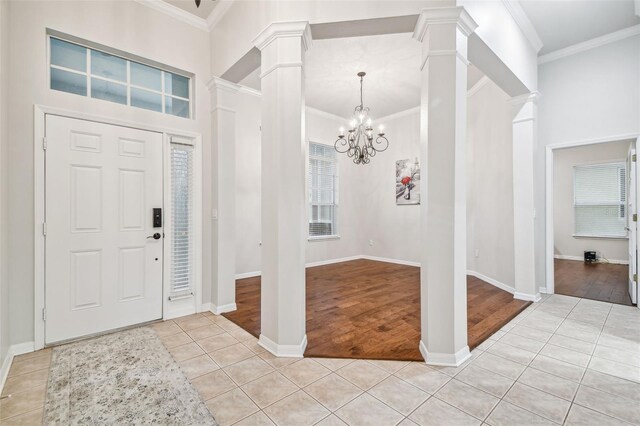 7410 Ambleside Dr, Land O Lakes, FL 34637 - entrance foyer featuring decorative columns, light tile patterned flooring, crown molding, a chandelier, and baseboards