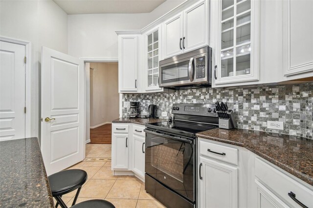 7410 Ambleside Dr, Land O Lakes, FL 34637 - kitchen with stainless steel microwave, black electric range oven, tasteful backsplash, and white cabinets