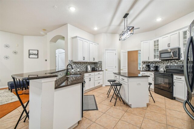 7410 Ambleside Dr, Land O Lakes, FL 34637 - kitchen featuring stainless steel microwave, black range with electric cooktop, a breakfast bar, a sink, and tasteful backsplash
