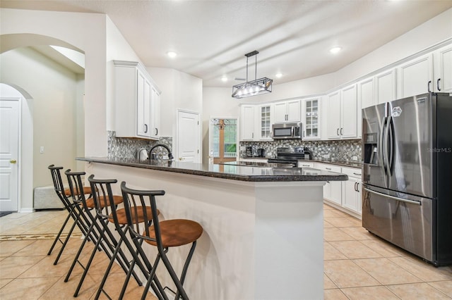 7410 Ambleside Dr, Land O Lakes, FL 34637 - kitchen with stainless steel appliances, a peninsula, light tile patterned floors, decorative backsplash, and a kitchen bar