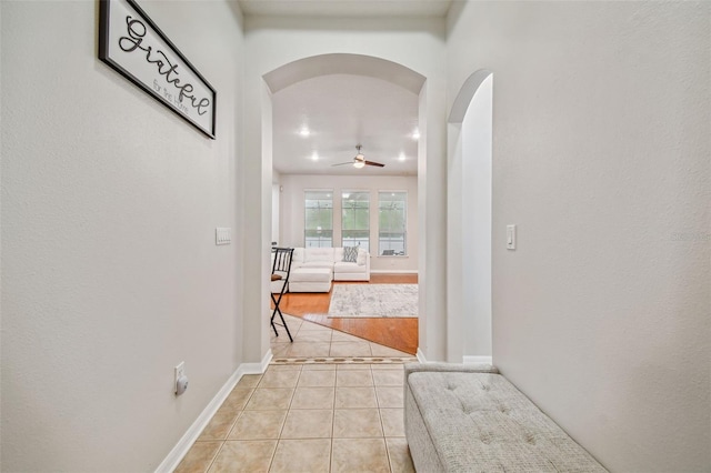 7410 Ambleside Dr, Land O Lakes, FL 34637 - hall with arched walkways, light tile patterned floors, and baseboards