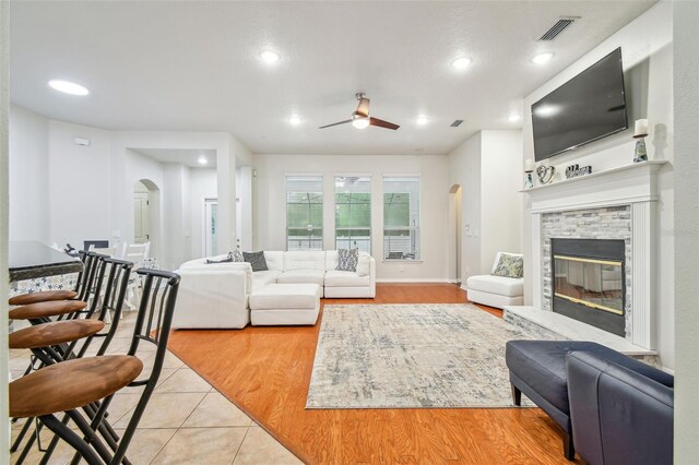 7410 Ambleside Dr, Land O Lakes, FL 34637 - living area with arched walkways, a ceiling fan, a fireplace, light tile patterned floors, and recessed lighting