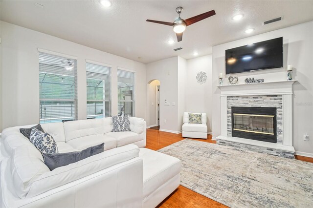 7410 Ambleside Dr, Land O Lakes, FL 34637 - living area with ceiling fan, wood finished floors, arched walkways, recessed lighting, and a stone fireplace