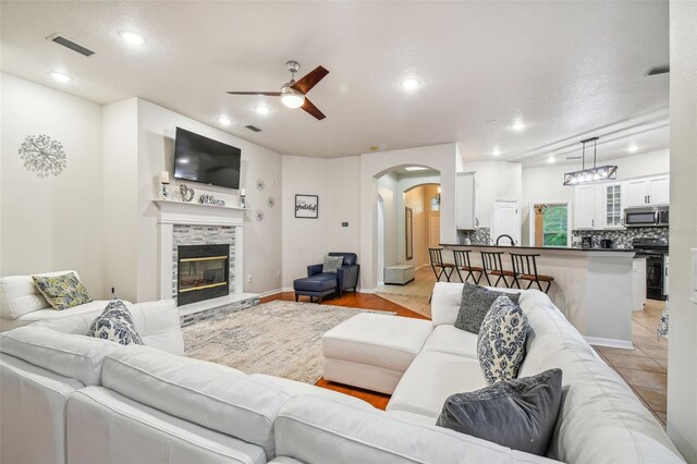 7410 Ambleside Dr, Land O Lakes, FL 34637 - living area with arched walkways, a ceiling fan, a fireplace, recessed lighting, and baseboards