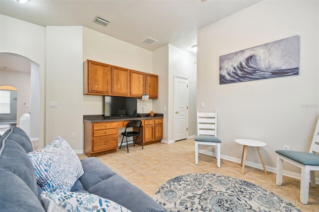 7410 Ambleside Dr, Land O Lakes, FL 34637 - office with arched walkways, built in desk, light tile patterned floors, and baseboards
