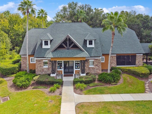 7410 Ambleside Dr, Land O Lakes, FL 34637 - view of front of property featuring stone siding, a front lawn, french doors, and a shingled roof