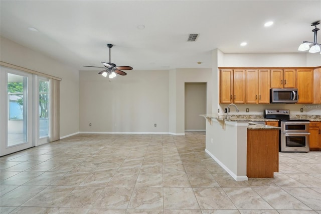 5340 Riva Ridge Dr, Wesley Chapel, FL 33544 - kitchen with stainless steel appliances, ceiling fan, light stone countertops, recessed lighting, and a peninsula