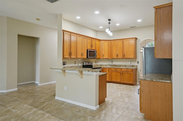 5340 Riva Ridge Dr, Wesley Chapel, FL 33544 - kitchen featuring stainless steel appliances, a peninsula, light stone counters, brown cabinets, and a breakfast bar