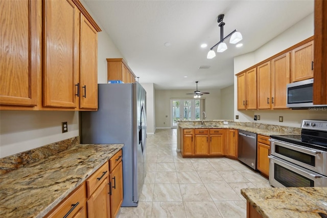 5340 Riva Ridge Dr, Wesley Chapel, FL 33544 - kitchen featuring stainless steel appliances, a peninsula, brown cabinetry, light marble finish floors, and a sink