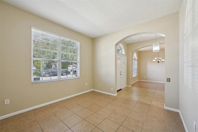 5340 Riva Ridge Dr, Wesley Chapel, FL 33544 - spare room featuring a chandelier, arched walkways, light tile patterned floors, and baseboards