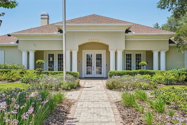5340 Riva Ridge Dr, Wesley Chapel, FL 33544 - property entrance featuring french doors, stucco siding, a chimney, and roof with shingles