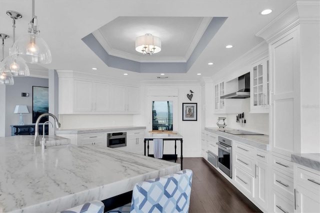 555 5th Ave NE Unit 1032, Saint Petersburg, FL 33701 - kitchen with wall chimney exhaust hood, stainless steel oven, black electric stovetop, dark wood-style flooring, and white cabinetry