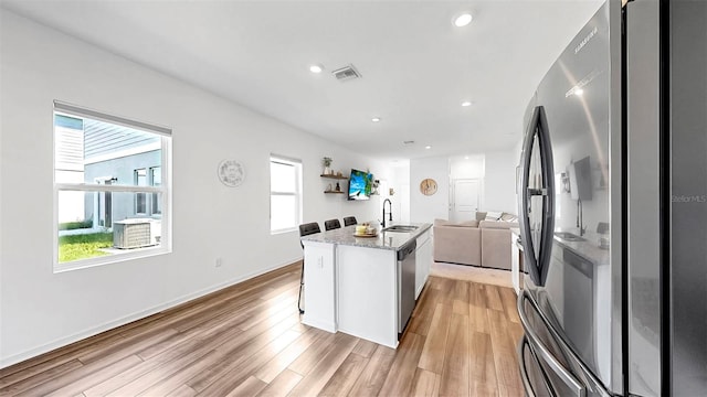 35552 Shade Fern Ln, Zephyrhills, FL 33541 - kitchen featuring a sink, open floor plan, light wood-type flooring, stainless steel appliances, and white cabinetry