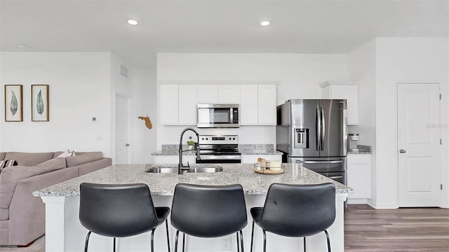 35552 Shade Fern Ln, Zephyrhills, FL 33541 - kitchen featuring stainless steel appliances, a sink, a kitchen island with sink, dark wood-style flooring, and a kitchen bar