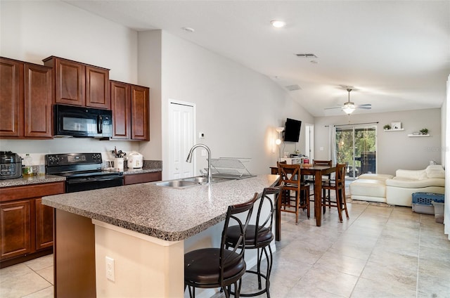 17334 White Mangrove Dr, Wimauma, FL 33598 - kitchen featuring black appliances, vaulted ceiling, a sink, a breakfast bar area, and open floor plan
