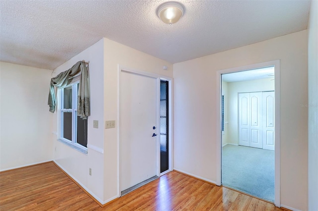 3053 Gregor Ct, Palm Harbor, FL 34684 - entrance foyer with light wood finished floors, a textured ceiling, and baseboards