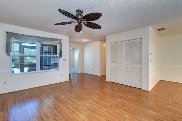 3053 Gregor Ct, Palm Harbor, FL 34684 - unfurnished living room featuring light wood-style flooring, a textured ceiling, a ceiling fan, and baseboards