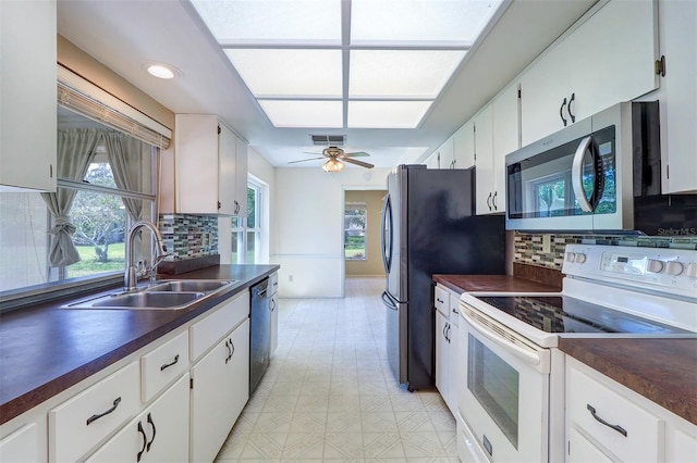 3053 Gregor Ct, Palm Harbor, FL 34684 - kitchen with appliances with stainless steel finishes, dark countertops, a sink, tasteful backsplash, and white cabinetry