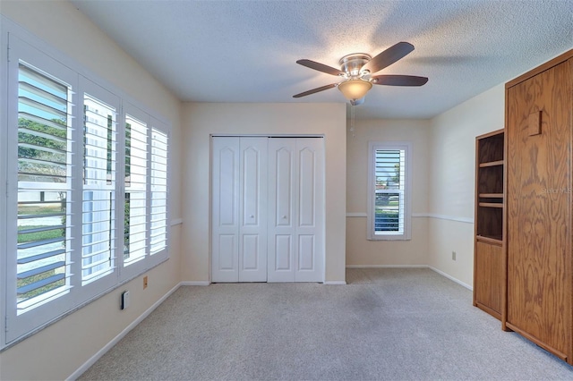 3053 Gregor Ct, Palm Harbor, FL 34684 - unfurnished bedroom featuring light carpet, a textured ceiling, a closet, baseboards, and a ceiling fan
