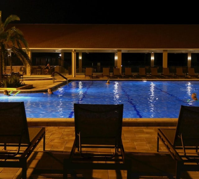 3053 Gregor Ct, Palm Harbor, FL 34684 - pool at night featuring a patio and a community pool