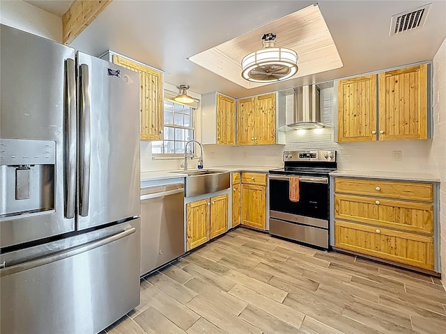 602 Mindy Dr, Largo, FL 33771 - kitchen featuring stainless steel appliances, a sink, wall chimney exhaust hood, light countertops, and light wood finished floors