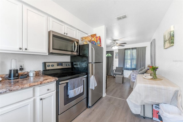 kitchen with stainless steel appliances, white cabinetry, light wood-style floors, a ceiling fan, and a textured ceiling