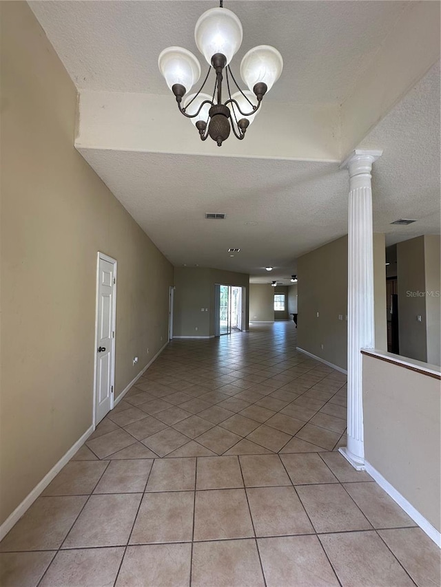 13632 Deventer Ct, Hudson, FL 34667 - unfurnished room with a textured ceiling, light tile patterned floors, a chandelier, baseboards, and ornate columns