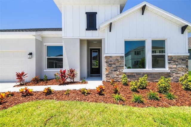 view of front of house with board and batten siding, an attached garage, and stone siding