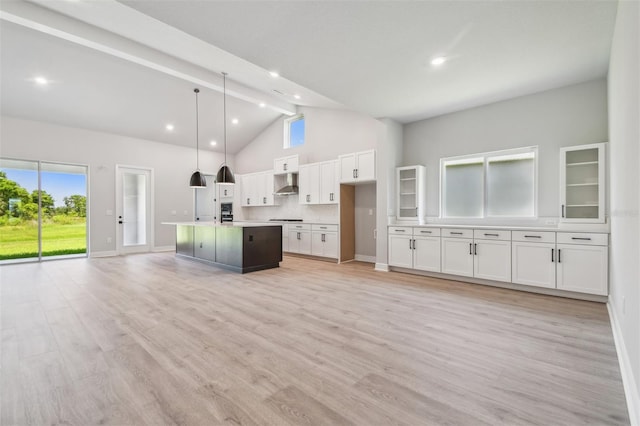 kitchen featuring high vaulted ceiling, white cabinetry, a center island with sink, open floor plan, and exhaust hood