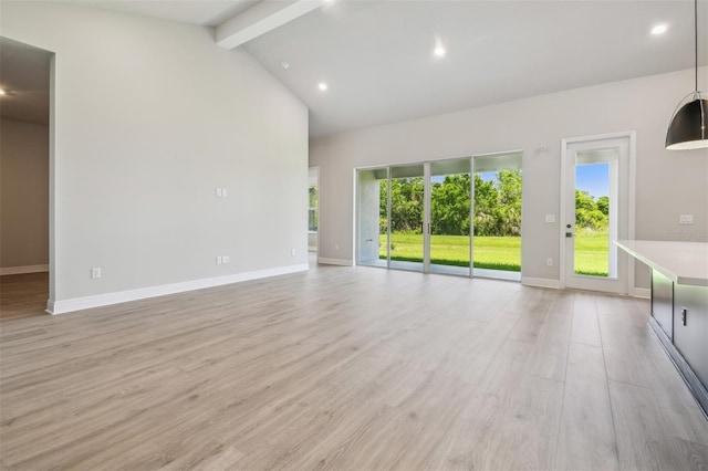 unfurnished living room with beamed ceiling, plenty of natural light, light wood-type flooring, baseboards, and high vaulted ceiling