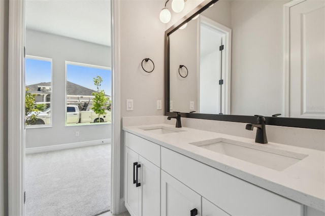 bathroom with double vanity and baseboards
