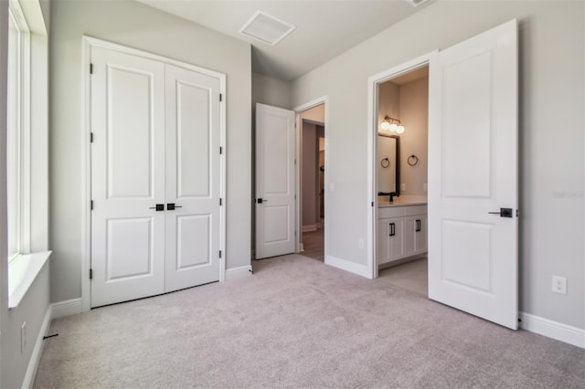 unfurnished bedroom with light carpet, a closet, and baseboards