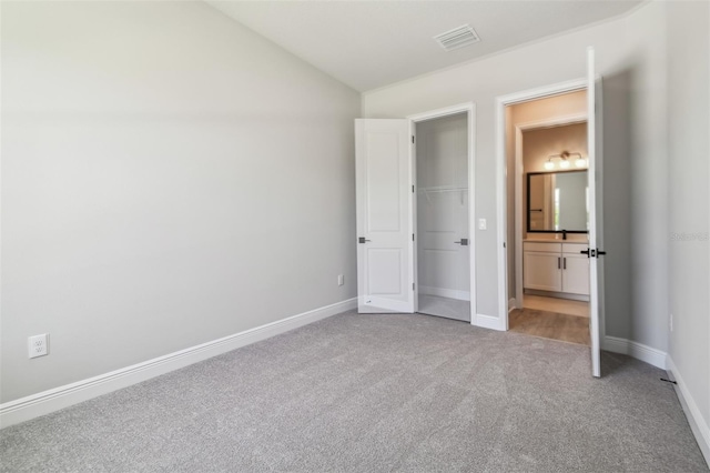 unfurnished bedroom featuring carpet flooring, lofted ceiling, baseboards, and ensuite bath