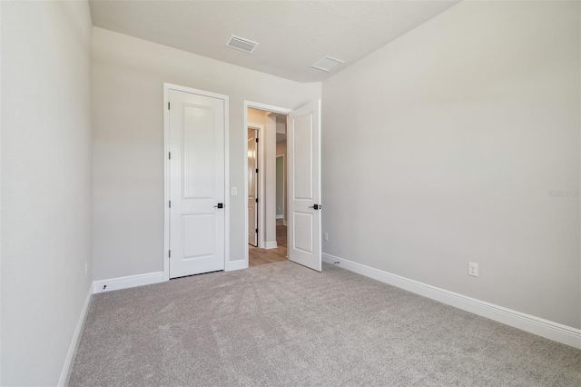 unfurnished bedroom featuring light carpet and baseboards