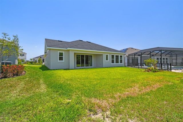 rear view of house featuring stucco siding, a yard, a lanai, and a pool
