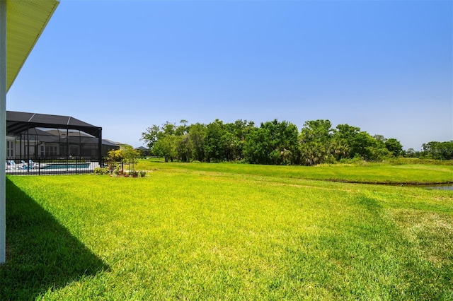view of green lawn with an outdoor pool and glass enclosure