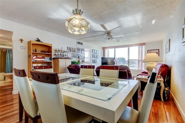7465 Bay Island Dr S Unit 213, South Pasadena, FL 33707 - dining area with a textured ceiling, wood finished floors, ceiling fan, and baseboards