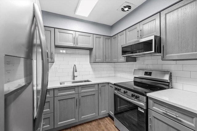 5051 Bonito Dr, New Port Richey, FL 34652 - kitchen with stainless steel appliances, gray cabinets, a sink, and decorative backsplash