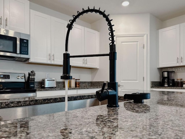 6444 Bar S Bar Trl, Zephyrhills, FL 33541 - kitchen featuring stainless steel appliances, white cabinetry, dark stone countertops, recessed lighting, and a sink