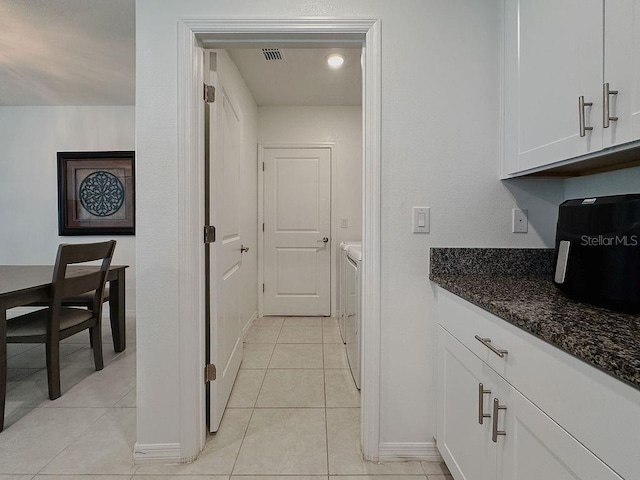 6444 Bar S Bar Trl, Zephyrhills, FL 33541 - kitchen with separate washer and dryer, white cabinetry, dark stone counters, baseboards, and light tile patterned floors