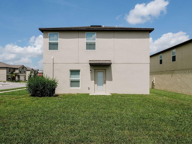6444 Bar S Bar Trl, Zephyrhills, FL 33541 - back of house featuring stucco siding and a yard