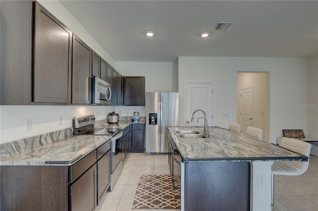 33062 Frosted Clover Way, Wesley Chapel, FL 33545 - kitchen featuring appliances with stainless steel finishes, a sink, light tile patterned flooring, dark brown cabinets, and recessed lighting