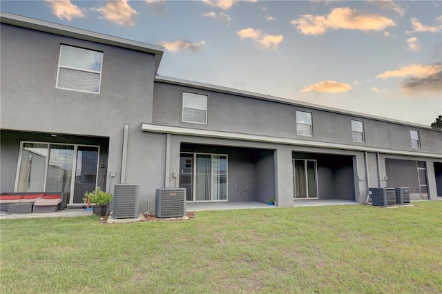 33062 Frosted Clover Way, Wesley Chapel, FL 33545 - rear view of house with stucco siding, central air condition unit, and a lawn